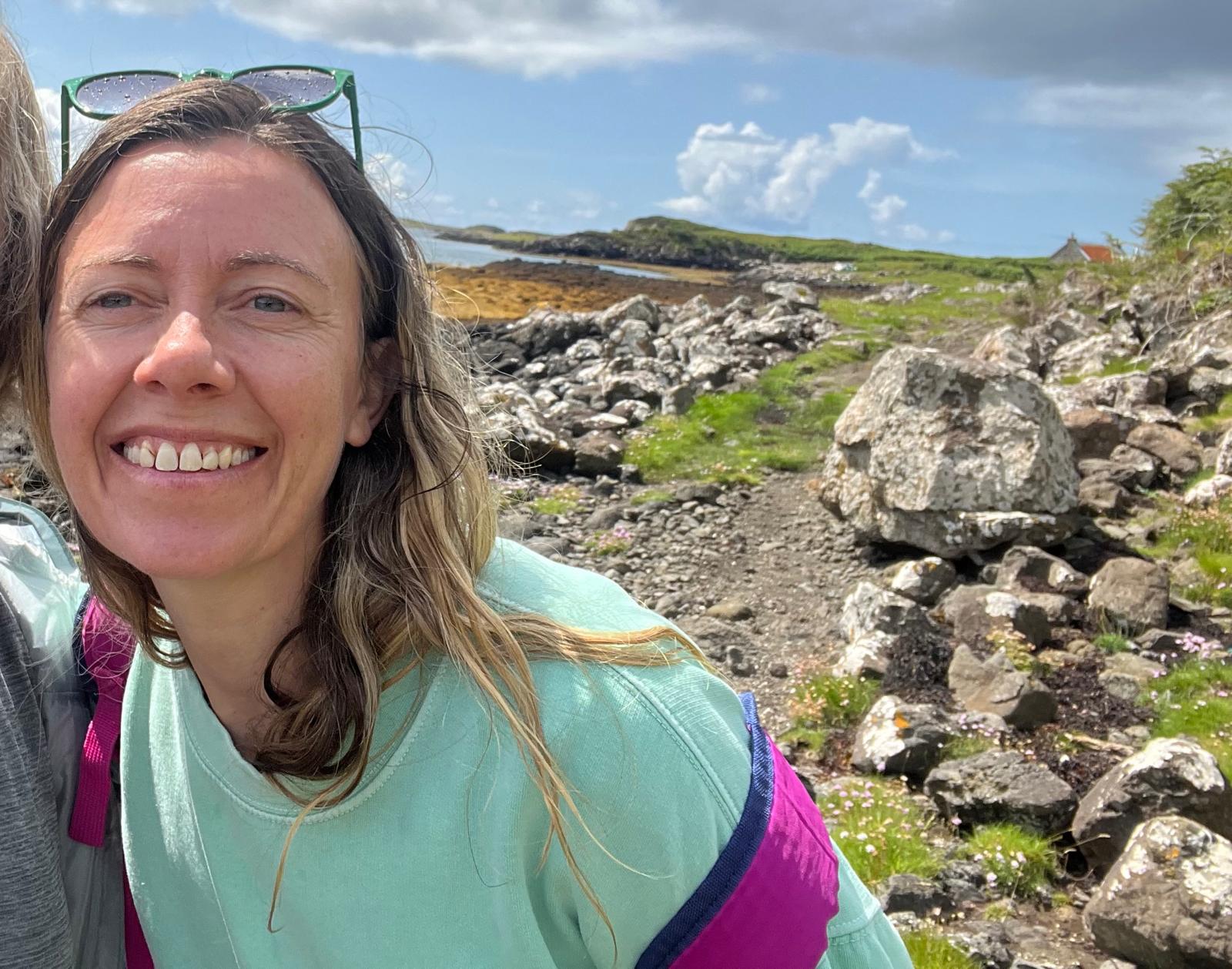 Laura, grinning at the camera on Ulva next to the sea